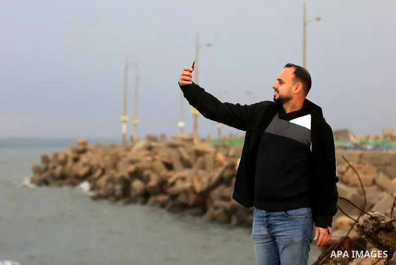 A Palestinian man takes a selife during a rainy day at seaport of Gaza city on December 9, 2019. Photo by Yasser Qudih