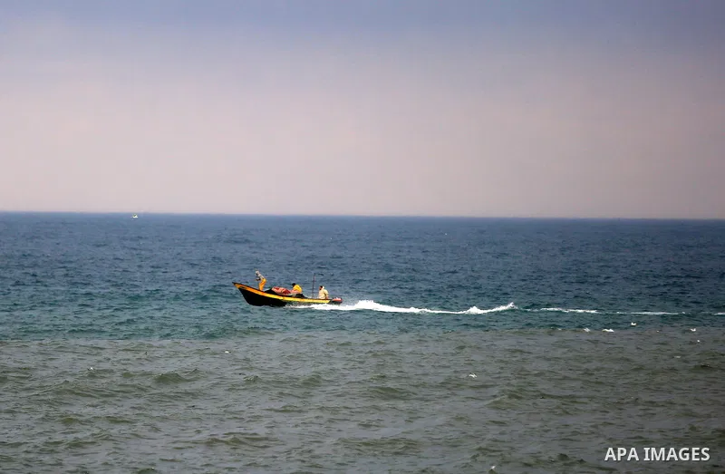 A Palestinian fisherman rides his boat during a rainy day at the coast of Gaza city. Photo by Yasser Qudih