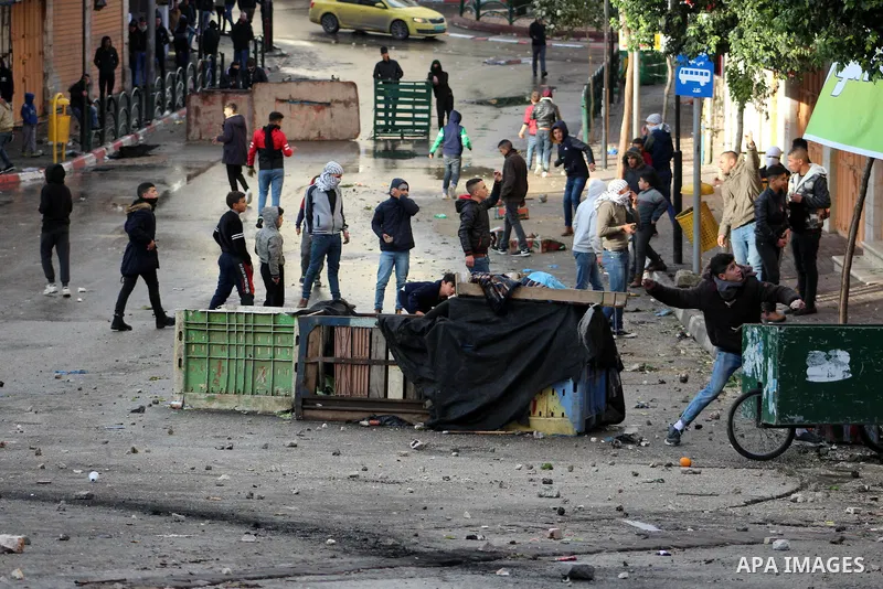 Palestinian protesters hurl stones towards Israeli security forces during a protest over a U.S. decision on Jewish settlements, in the West Bank city of Hebron on December 9, 2019. Photo by Mosab Shawer