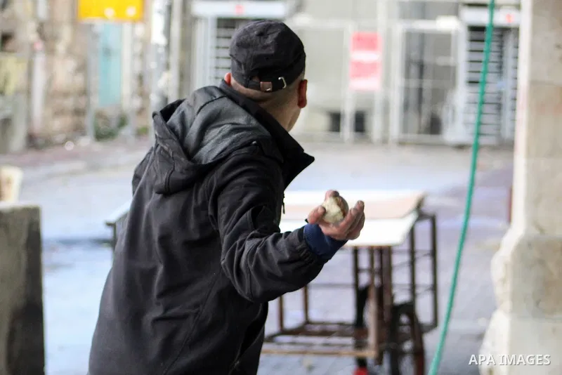 A Palestinian protester hurls a stone towards Israeli security forces during a protest over a U.S. decision on Jewish settlements, in the West Bank city of Hebron on December 9, 2019. Photo by Mosab Shawer