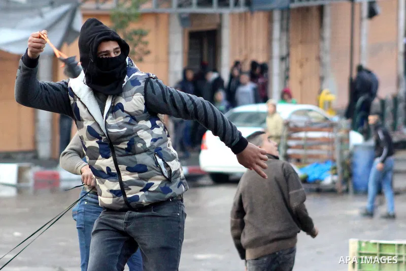 A Palestinian protester hurls a stone towards Israeli security forces during a protest over a U.S. decision on Jewish settlements, in the West Bank city of Hebron on December 9, 2019. Photo by Mosab Shawer