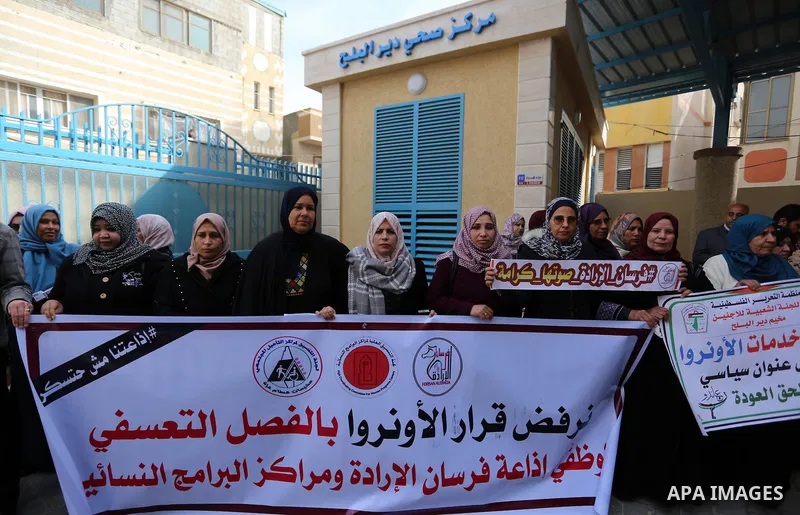 Palestinians hold placards during a rally in support of the headquarters United Nations Relief and Works Agency (UNRWA), at a United Nations-run health center in Dair Al Balah in the center of Gaza strip on December 12,...