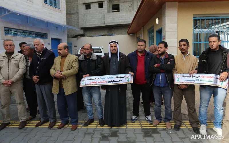 Palestinians hold placards during a rally in support of the headquarters United Nations Relief and Works Agency (UNRWA), at a United Nations-run health center in Dair Al Balah in the center of Gaza strip on December 12,...