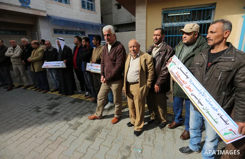 Palestinians hold placards during a rally in support of the headquarters United Nations Relief and Works Agency (UNRWA), at a United Nations-run health center in Dair Al Balah in the center of Gaza strip on December 12,...