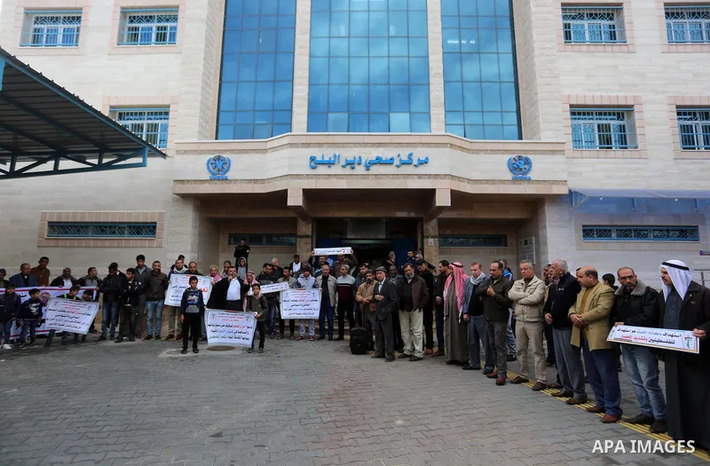 Palestinians hold placards during a rally in support of the headquarters United Nations Relief and Works Agency (UNRWA), at a United Nations-run health center in Dair Al Balah in the center of Gaza strip on December 12,...