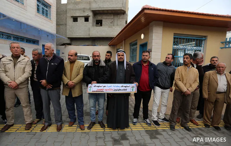 Palestinians hold placards during a rally in support of the headquarters United Nations Relief and Works Agency (UNRWA), at a United Nations-run health center in Dair Al Balah in the center of Gaza strip on December 12,...