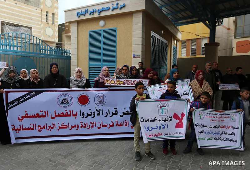 Palestinians hold placards during a rally in support of the headquarters United Nations Relief and Works Agency (UNRWA), at a United Nations-run health center in Dair Al Balah in the center of Gaza strip on December 12,...
