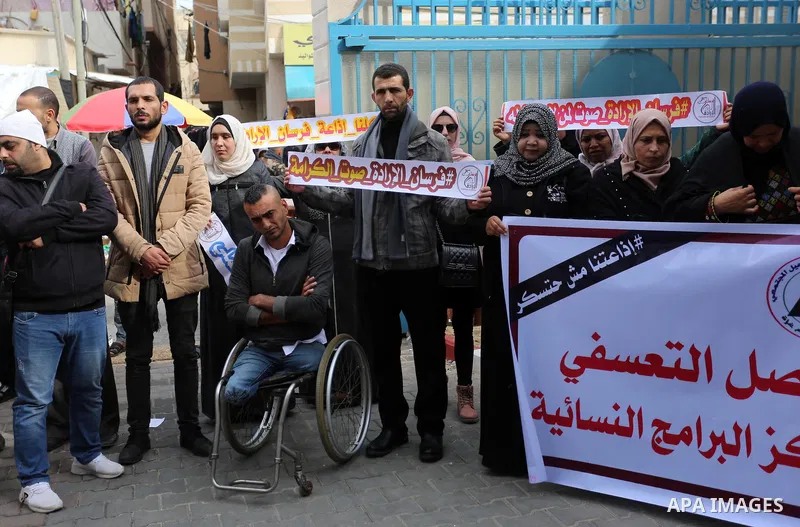 Palestinians hold placards during a rally in support of the headquarters United Nations Relief and Works Agency (UNRWA), at a United Nations-run health center in Dair Al Balah in the center of Gaza strip on December 12,...
