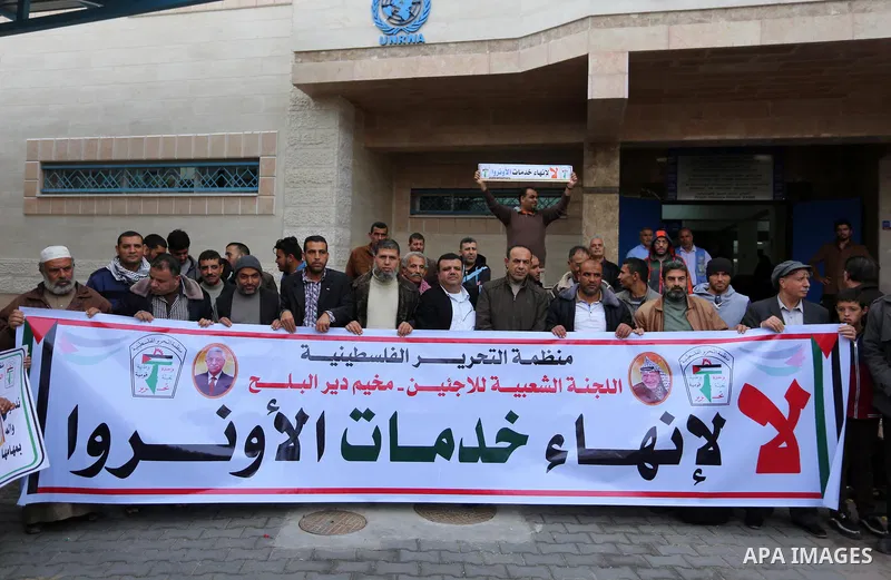 Palestinians hold placards during a rally in support of the headquarters United Nations Relief and Works Agency (UNRWA), at a United Nations-run health center in Dair Al Balah in the center of Gaza strip on December 12,...