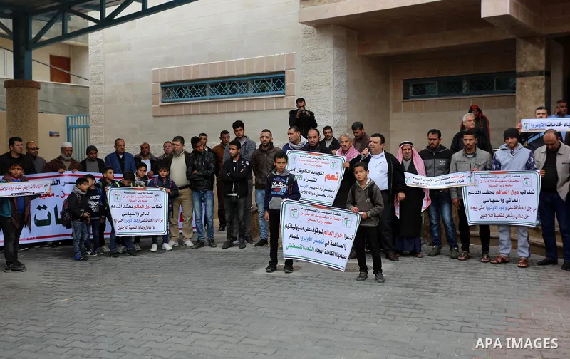 Palestinians hold placards during a rally in support of the headquarters United Nations Relief and Works Agency (UNRWA), at a United Nations-run health center in Dair Al Balah in the center of Gaza strip on December 12,...