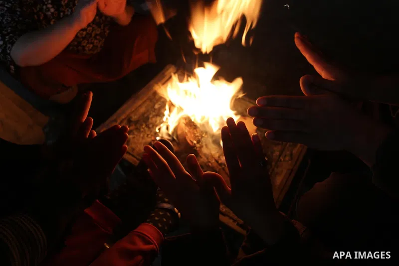 Palestinians warm themselves by a fire during a rainy day in Dair Al Balah in the center of Gaza strip on December 15, 2019. Photo by Ashraf Amra