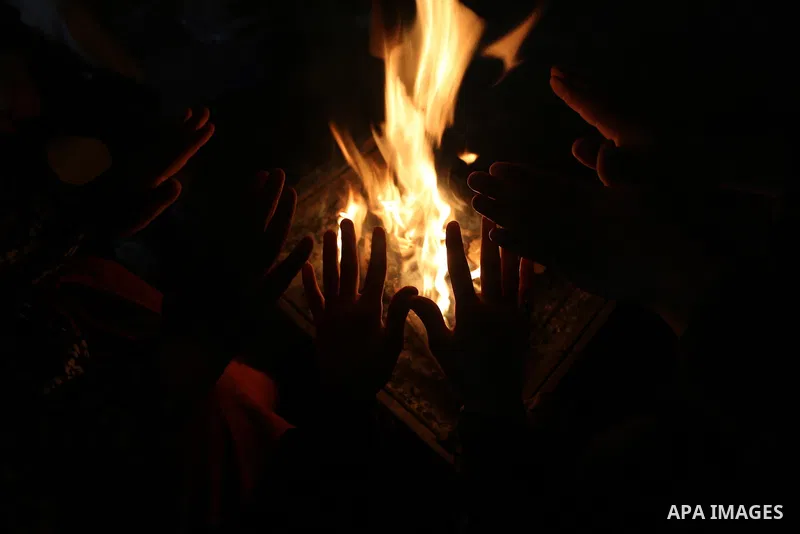 Palestinians warm themselves by a fire during a rainy day in Dair Al Balah in the center of Gaza strip on December 15, 2019. Photo by Ashraf Amra
