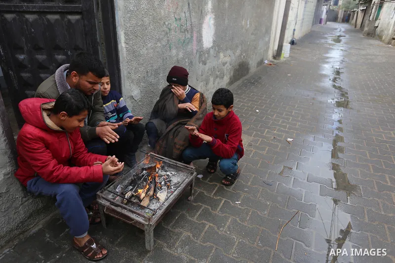 Palestinians warm themselves by a fire during a rainy day in Dair Al Balah in the center of Gaza strip on December 15, 2019. Photo by Ashraf Amra