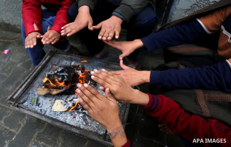 Palestinians warm themselves by a fire during a rainy day in Dair Al Balah in the center of Gaza strip on December 15, 2019. Photo by Ashraf Amra