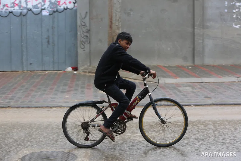 Palestinians walk in a street during a rainy day in Dair Al Balah in the center of Gaza strip on December 15, 2019. Photo by Ashraf Amra