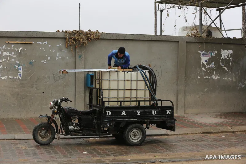 Palestinians walk in a street during a rainy day in Dair Al Balah in the center of Gaza strip on December 15, 2019. Photo by Ashraf Amra