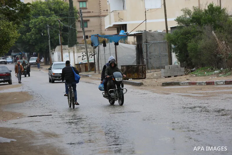 Palestinians walk in a street during a rainy day in Dair Al Balah in the center of Gaza strip on December 15, 2019. Photo by Ashraf Amra