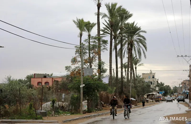 Palestinians walk in a street during a rainy day in Dair Al Balah in the center of Gaza strip on December 15, 2019. Photo by Ashraf Amra