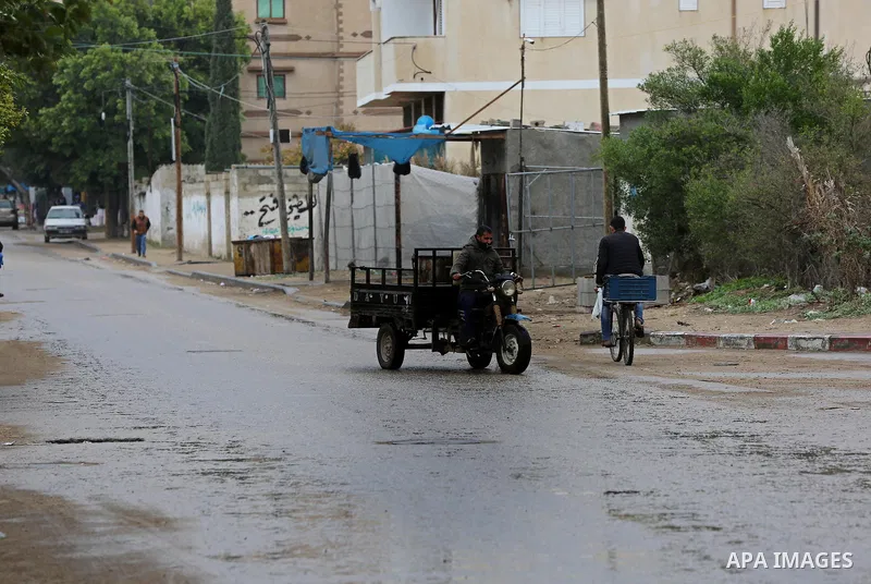 Palestinians walk in a street during a rainy day in Dair Al Balah in the center of Gaza strip on December 15, 2019. Photo by Ashraf Amra