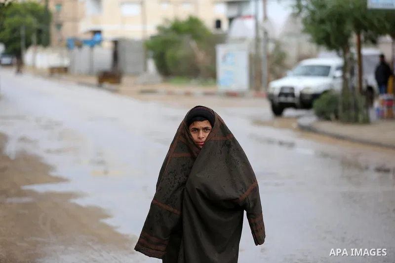 A Palestinian boy walks in a street during a rainy day in Dair Al Balah in the center of Gaza strip on December 15, 2019. Photo by Ashraf Amra