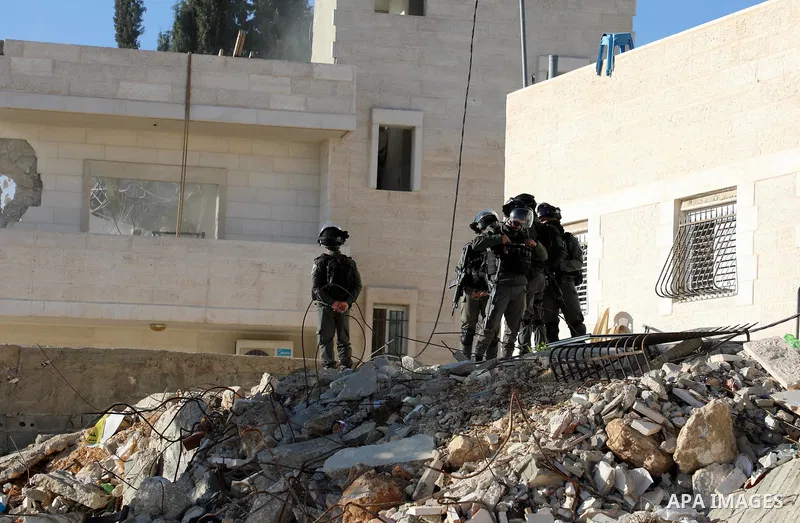 Israeli forces stand guard as an Israeli bulldozer demolishes a Palestinian building which does not have the Israeli needed permits in the neighbourhood of Issawiya, in the north of Jerusalem, on December 17, 2019. Photo...