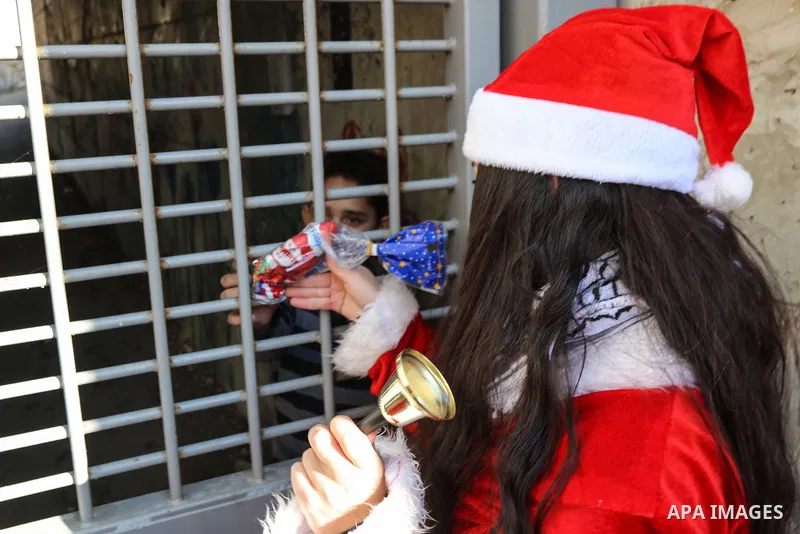 A Palestinian girl dressed as Santa Claus gives a gift to a Palestinian boy living on the other side of the Israeli barrier that separates Jerusalem from the West Bank, during an anti-Israel protest near Bethlehem on Dec...