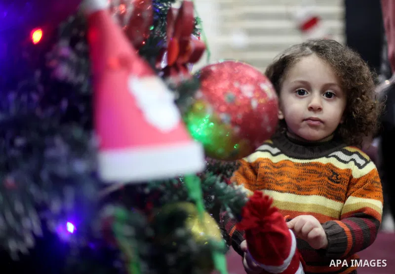 A Palestinian child stands next to the Christmas tree decorated with remants of the environment, in Gaza city on December 26, 2019. Photo by Mahmoud Ajjour