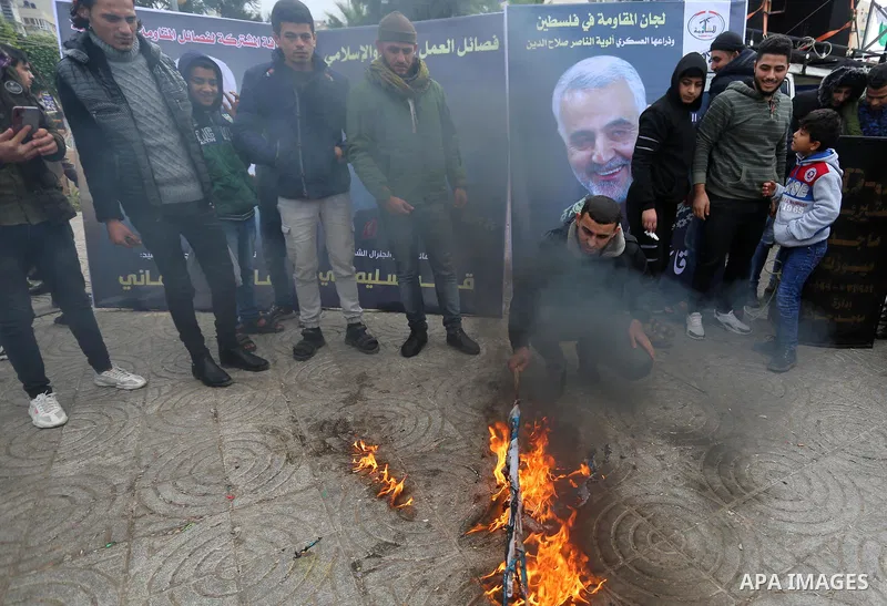 A Palestinian man burns flag of Israel and America during the consolation of the general Qasim Soleimani, in Gaza city, on January 4, 2020. Photo by Ashraf Amra