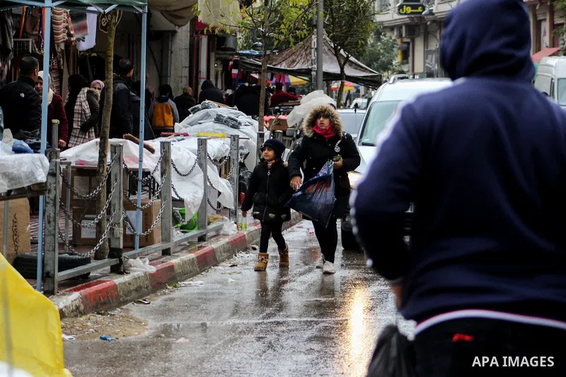 Palestinians walk in a street during a rainy day, in the West Bank city of Hebron, January 08, 2020. Photo by Mosab Shawer