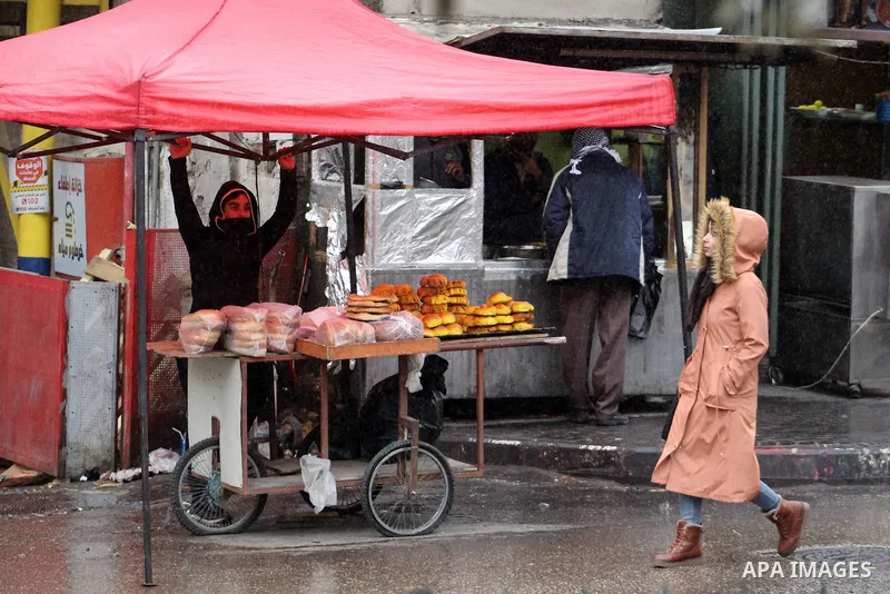 Palestinians walk in a street during a rainy day, in the West Bank city of Hebron, January 08, 2020. Photo by Mosab Shawer