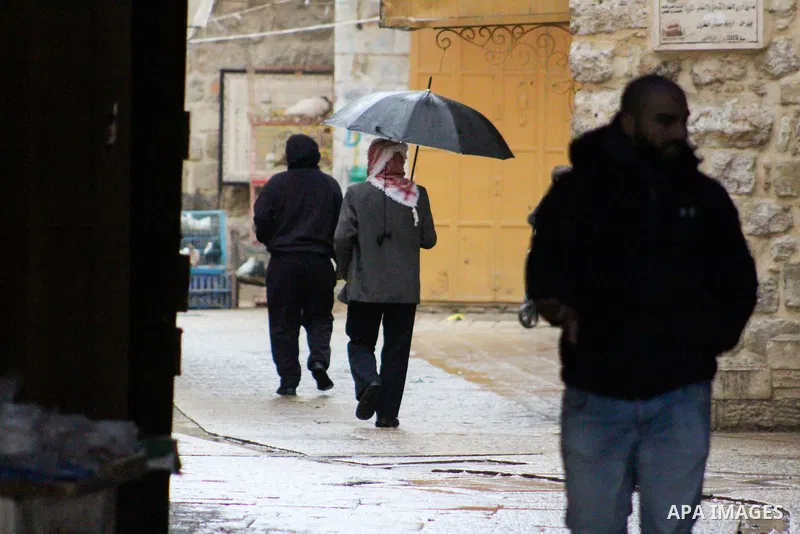 Palestinians walk in a street during a rainy day, in the West Bank city of Hebron, January 08, 2020. Photo by Mosab Shawer