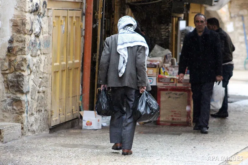 Palestinians walk in a street during a rainy day, in the West Bank city of Hebron, January 08, 2020. Photo by Mosab Shawer
