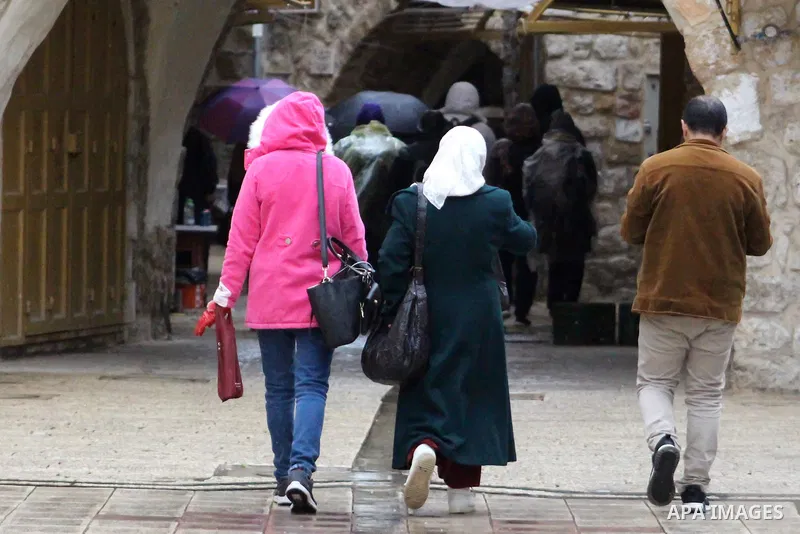 Palestinians walk in a street during a rainy day, in the West Bank city of Hebron, January 08, 2020. Photo by Mosab Shawer