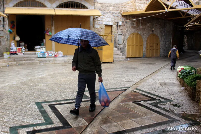 Palestinians walk in a street during a rainy day, in the West Bank city of Hebron, January 08, 2020. Photo by Mosab Shawer