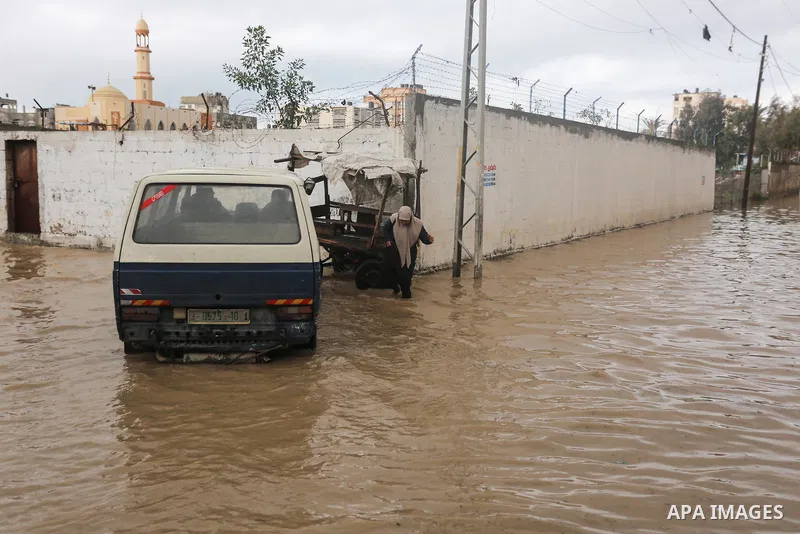 Palestinians walk in a flooded street following a heavy rain, in Gaza City on January 9, 2020. Photo by Ashraf Amra