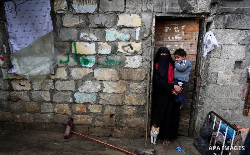 A Palestinian woman stands next to a cat during a cold weather spell in an empoverished neighbourhood on the outskirts in Gaza City on January 9, 2020. Photo by Ashraf Amra