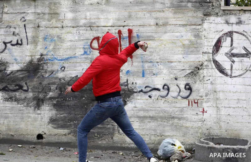 A Palestinian protester hurls stone towards Israeli troops during clashes against US President Donald Trump's expected peace plan proposal or Deal of the Century, in Arroub refugee camp north of the West Bank city of Heb...