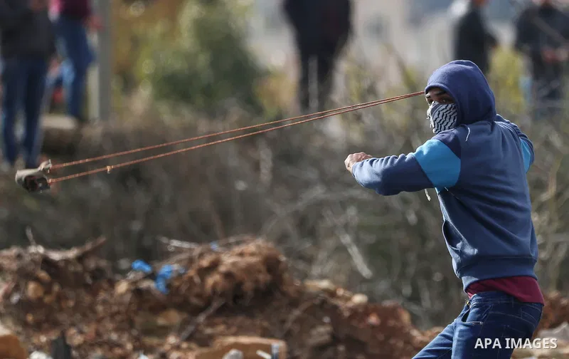 A Palestinian protester hurls a stone towards Israeli security forces during clashes with Palestinian protesters following a demonstration against US President Donald Trump's Century Deal "expected peace plan" near the s...