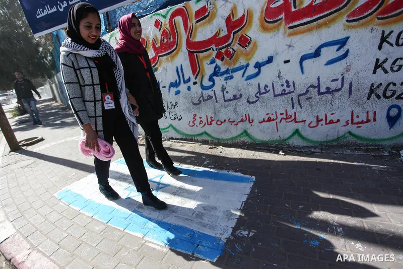 Palestinians walk past a mural entitled "Century deal falls", in Gaza city, on February 6, 2020. Photo by Mahmoud Ajjour