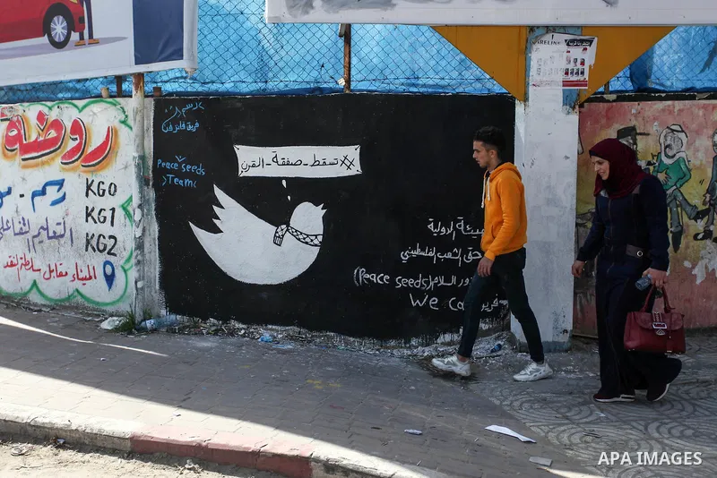 Palestinians walk past a mural entitled "Century deal falls", in Gaza city, on February 6, 2020. Photo by Mahmoud Ajjour