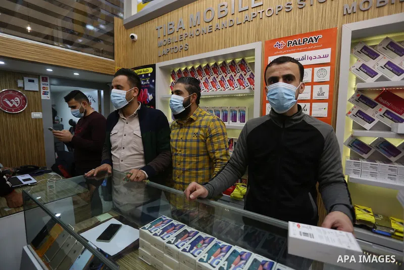 Palestinian men wearing masks, during a safety campaign to spread awareness about COVID-19 coronavirus disease, sell at a Mobile shop, in Khan Younis in the southern of Gaza strip, on March 7, 2020. Photo by Ashraf Amra