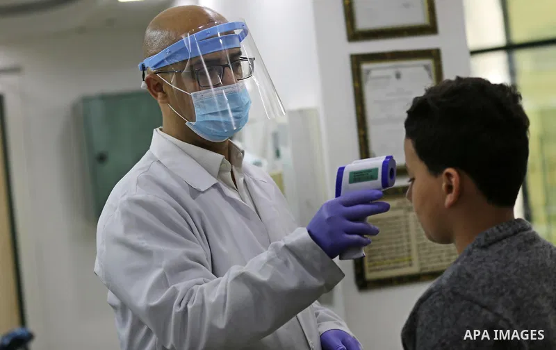 A Palestinian doctor uses a temperature test machine, for a medical examination to detect Coronavirus, in Gaza City on March 10, 2020. For most people, the new coronavirus causes only mild or moderate symptoms, such as f...