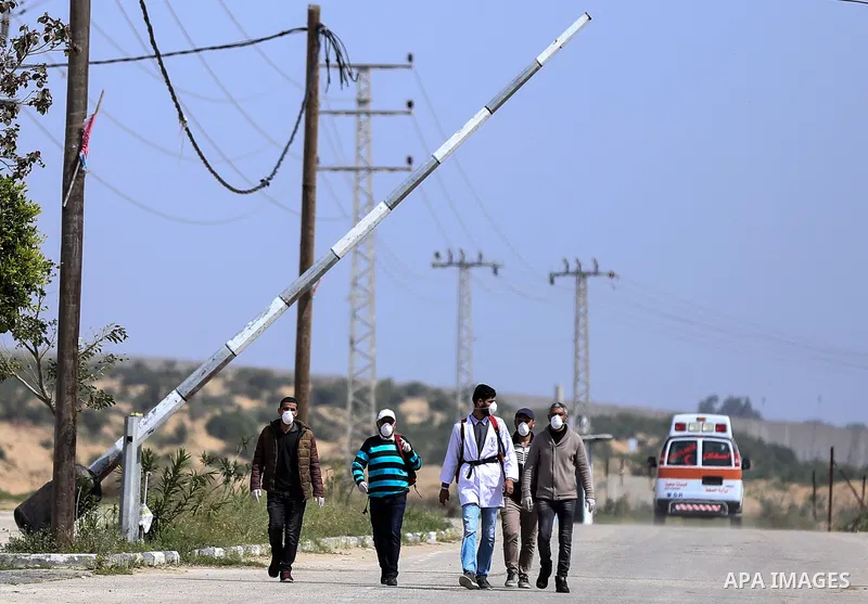 Palestinians wearing masks as a means of protection against the coronavirus COVID-19, stand outside the gate of Erez crossing with Israel in Beit Hanoun in the northern Gaza Strip on March 15, 2020. Palestinian goverment...