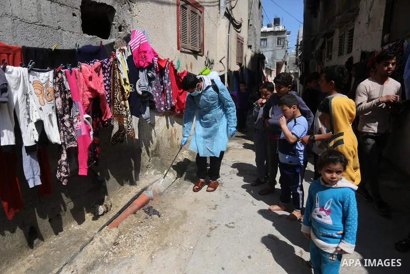 A Palestinian worker wearing protective gear, disinfects streets, as a preventive measure amid fears of the spread of the coronavirus COVID-19, at al-shati' refugee camp in Gaza City on March 16, 2020. Photo by Ashraf Am...