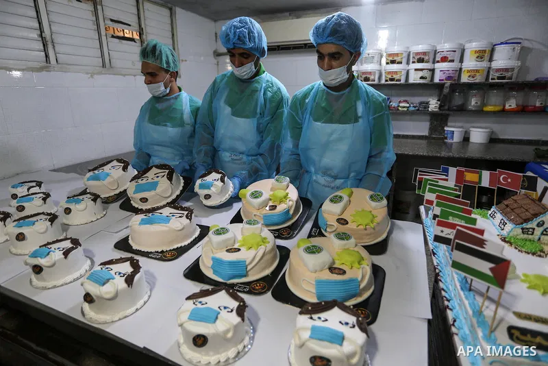 Palestinians put final touches on cakes that portrays a woman wearing a facemask with model of bottel of Dettol to sterilize, at their shop in Khan Yunis in the southern Gaza Strip on March 31, 2020. The United Nations h...