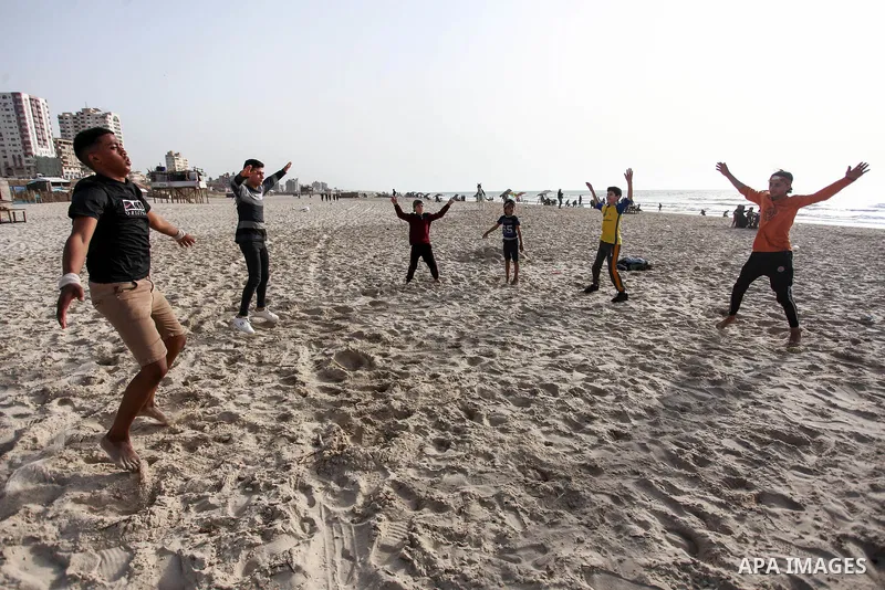 Palestinian children practice their gymnastics skill on the beach in Gaza City on, 19 April 2020. amid the novel coronavirus pandemic. Photo by Mahmoud Ajjour