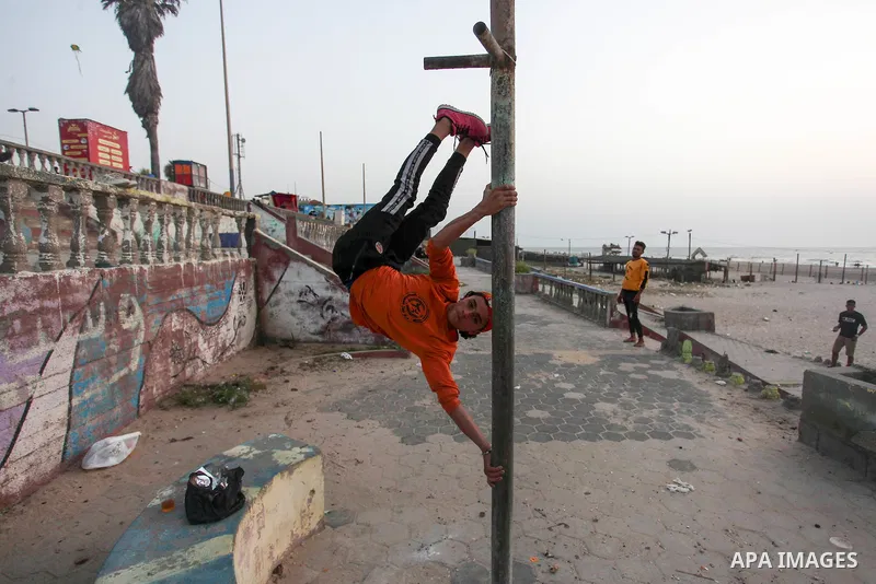 Palestinian children practice their gymnastics skill on the beach in Gaza City on, 19 April 2020. amid the novel coronavirus pandemic. Photo by Mahmoud Ajjour