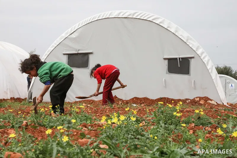 A photo taken on March 12, 2020 shows displaced Syrian girls plant at a makeshift camp in the northern Syrian city of Azaz. Photo by Nayef ALaboud