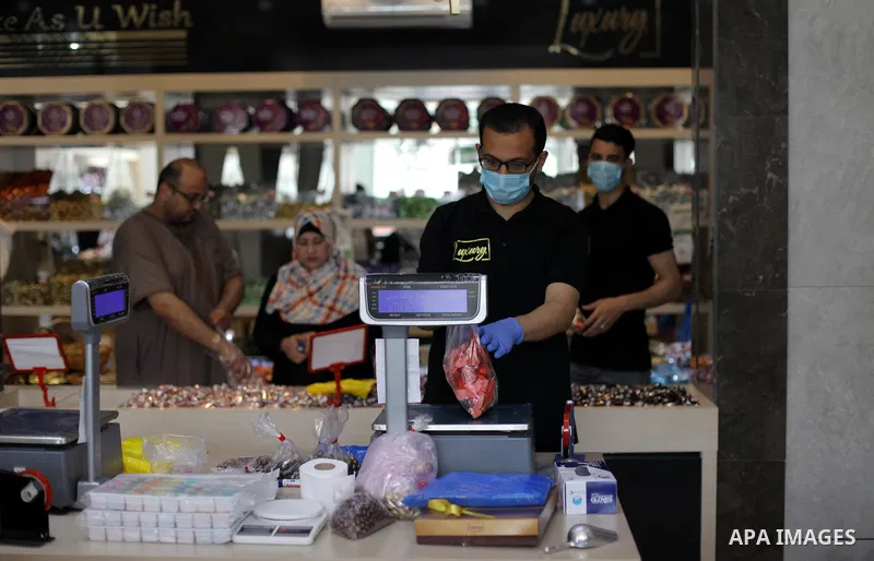 Palestinians wearing protective face-masks, sell chocolate for customers ahead of Eid al-Fitr holiday in Gaza City, on May 23, 2020. Photo by Mahmoud Ajjour