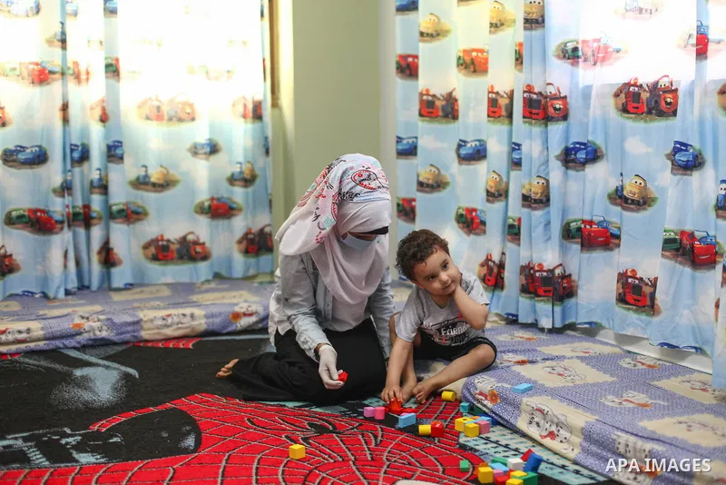 Palestinian Kindergarten teacher wearing a face mask and gloves, play with children after the decision to open the Kindergarten‎‏ after they were closed for nearly three months, as a precaution against the spread of the...
